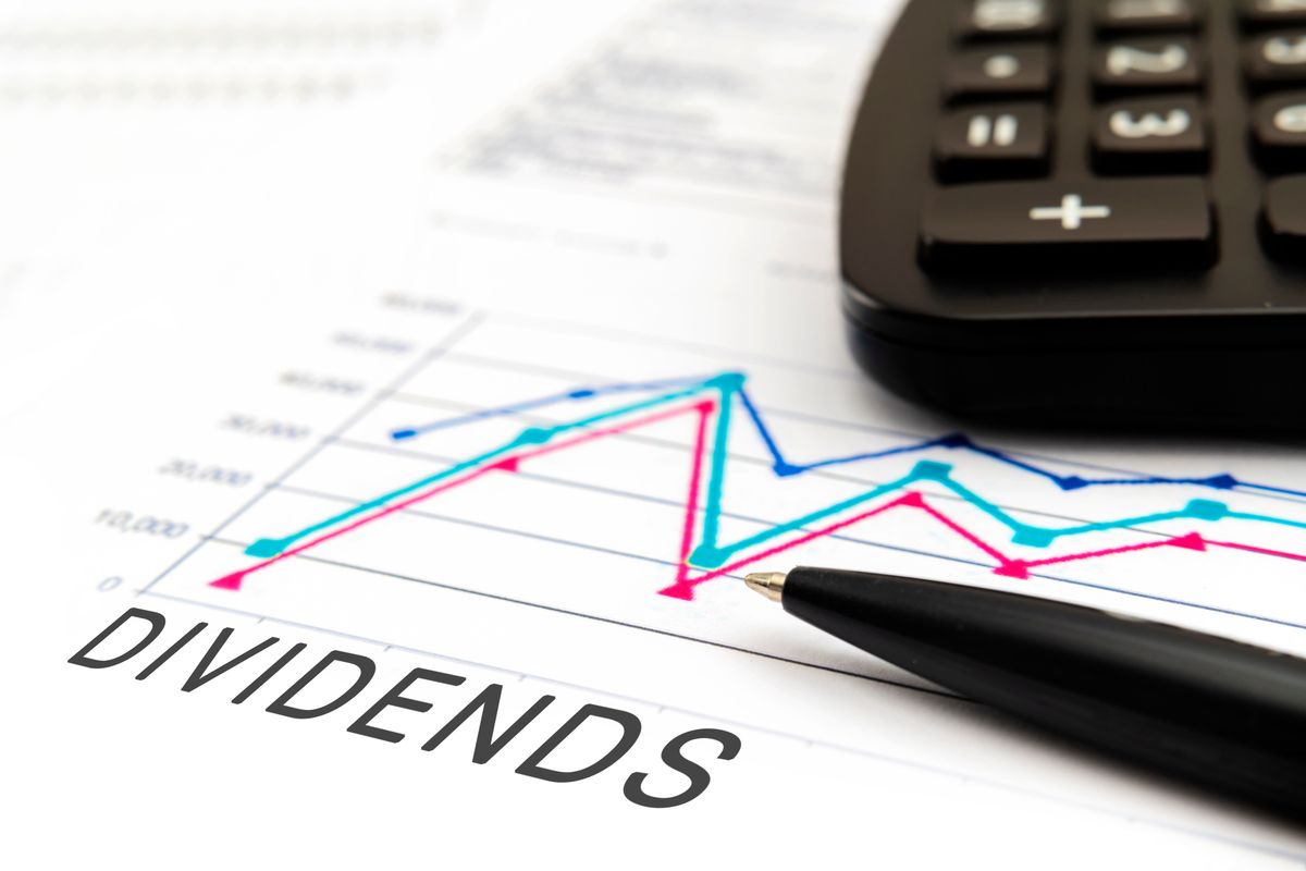 Calculator and pen on top of paper with line chart that says "dividends."
