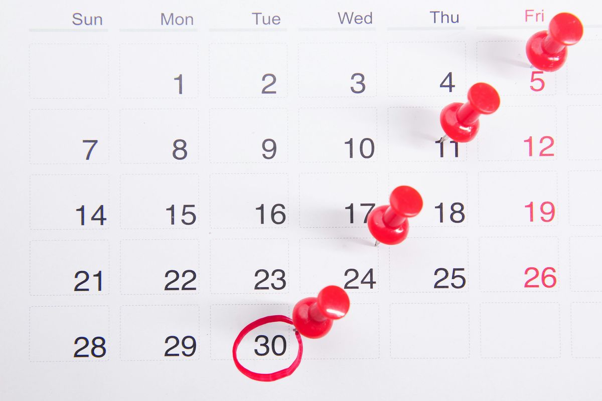 Calendar with red push pins and circled date.