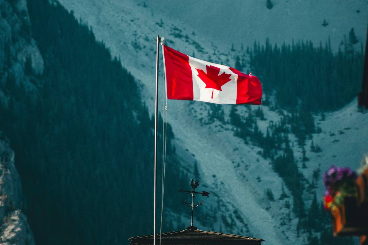 Canadian flag waving in front of a mountain landscape.
