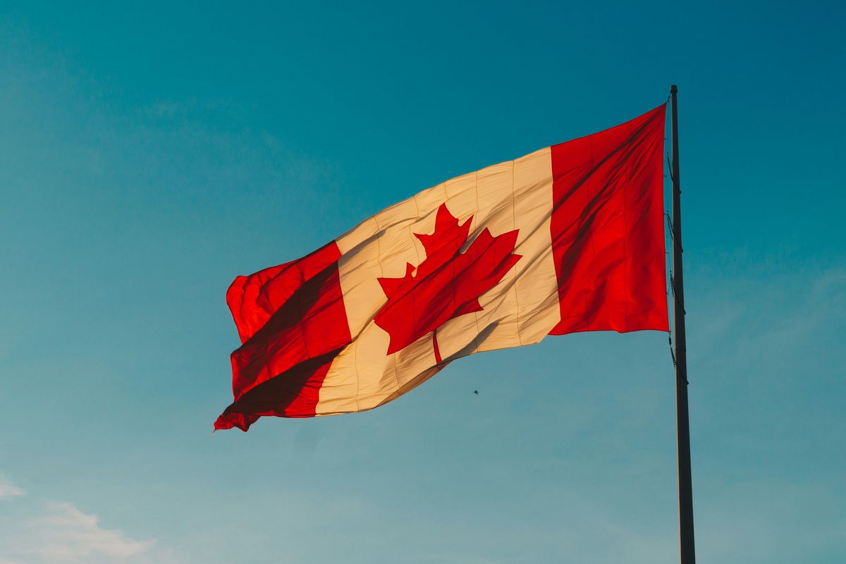 Canadian flag waving in front of blue sky.