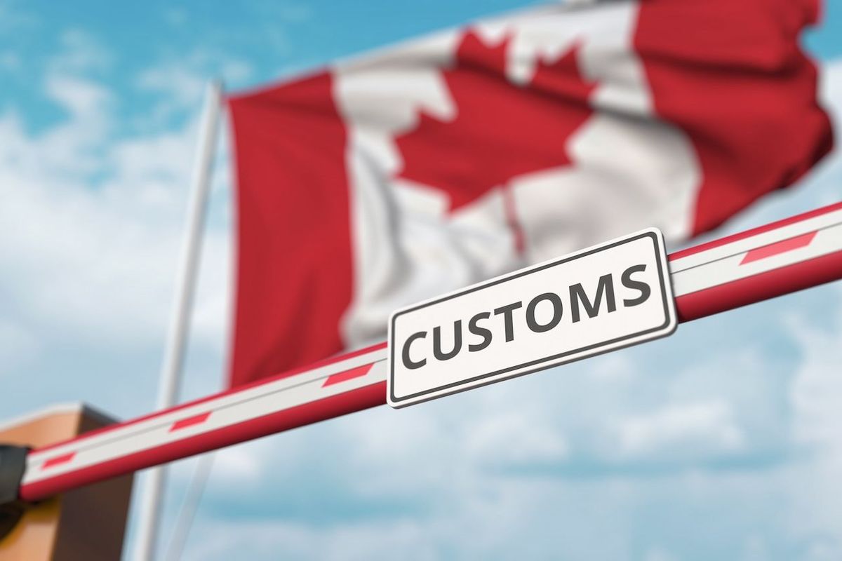 Canadian flag with a customs barricade in front of it.