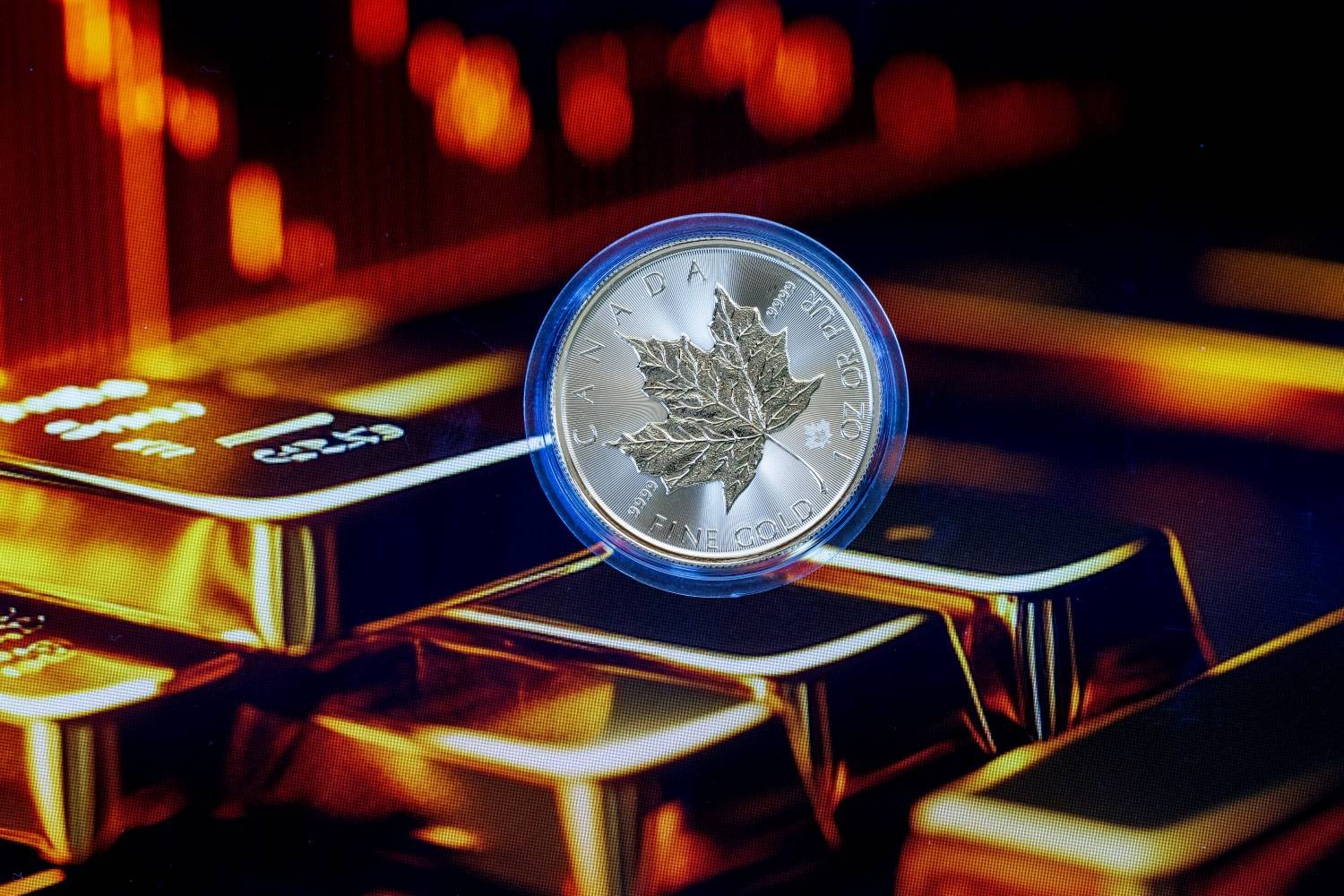 Canadian Maple Leaf gold coin floating over stacked gold bars with glowing red lights.