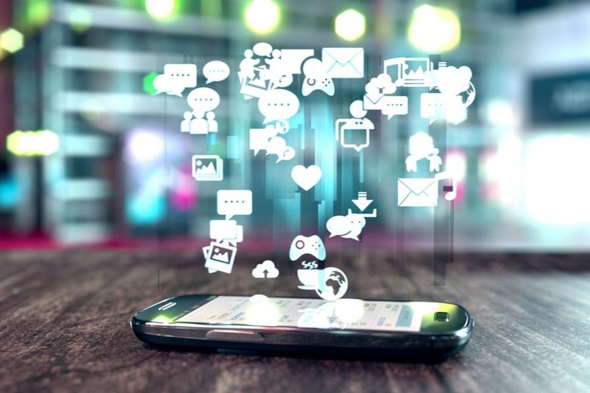 cell phone lying on table with app icons floating above it