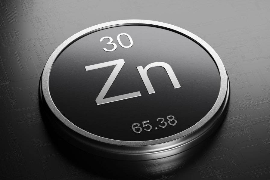 Circular zinc emblem with metallic rim on dark surface.