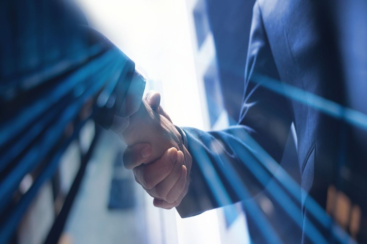 Close-up of two people in suits shaking hands with blue lights overlay.
