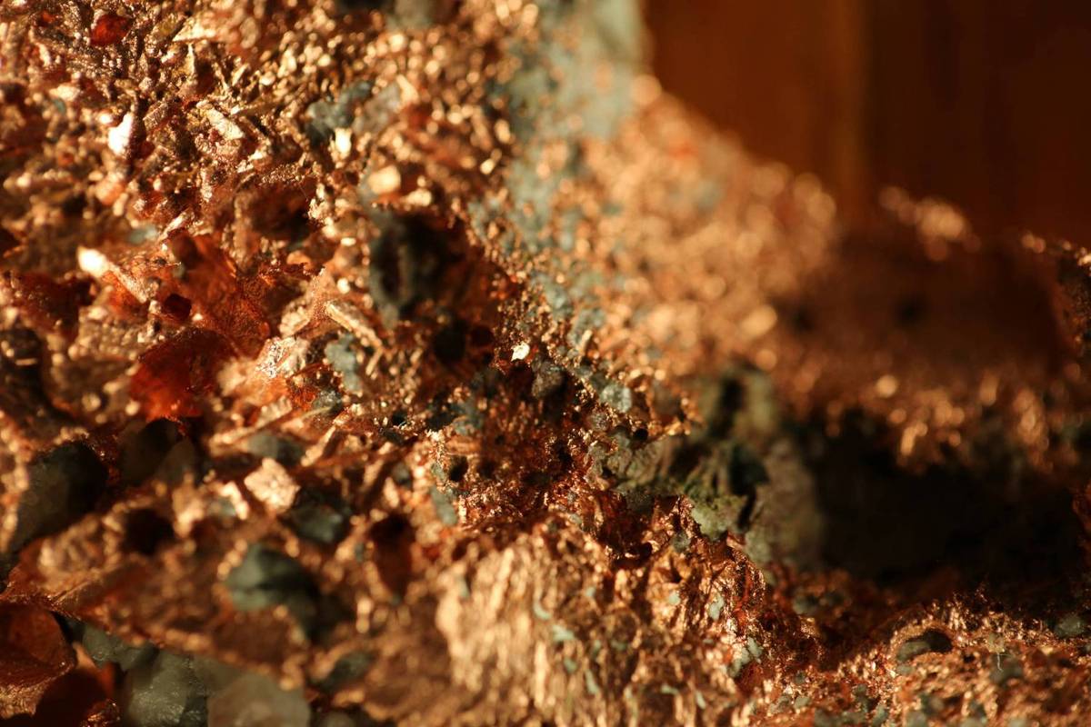 Closeup of a rough, metallic copper surface with reddish-brown and gray hues.