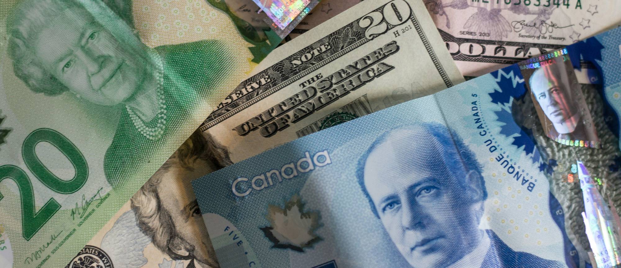 Closeup of Canadian and US currency bills overlapping.