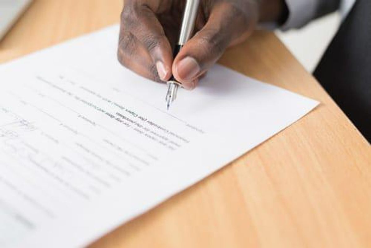 closeup of hand signing contract