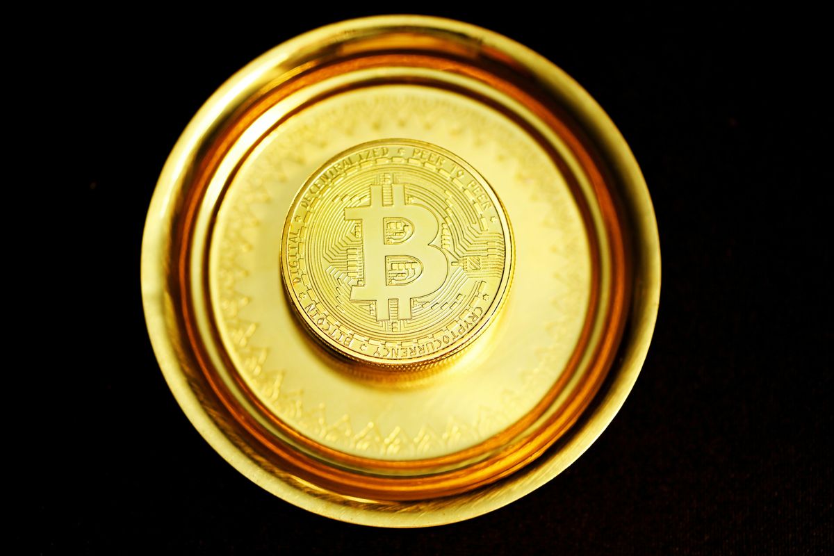 Closeup of single gold Bitcoin on a dark background.
