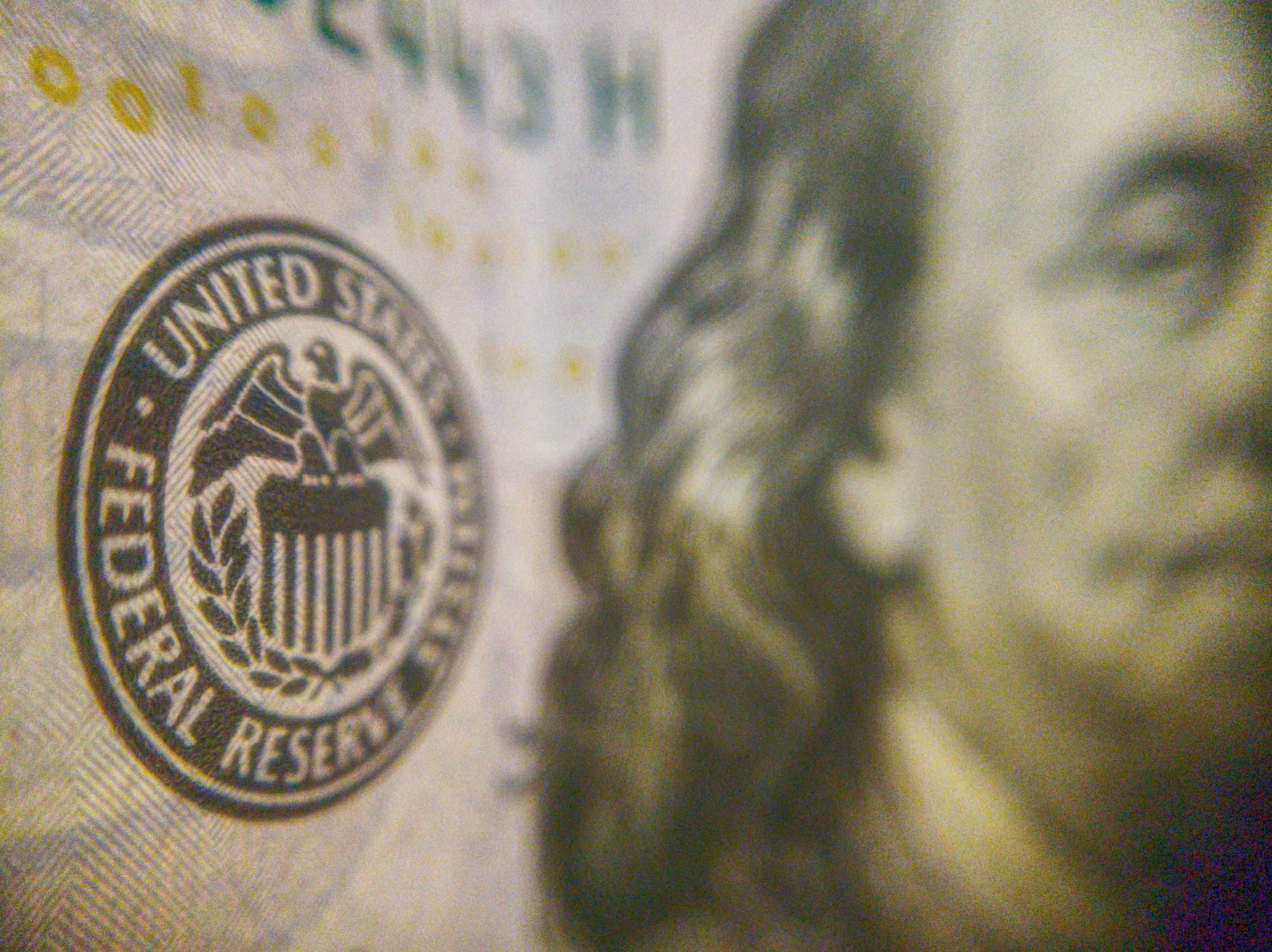 Closeup of US Federal Reserve seal on US bill with partial portrait visible.