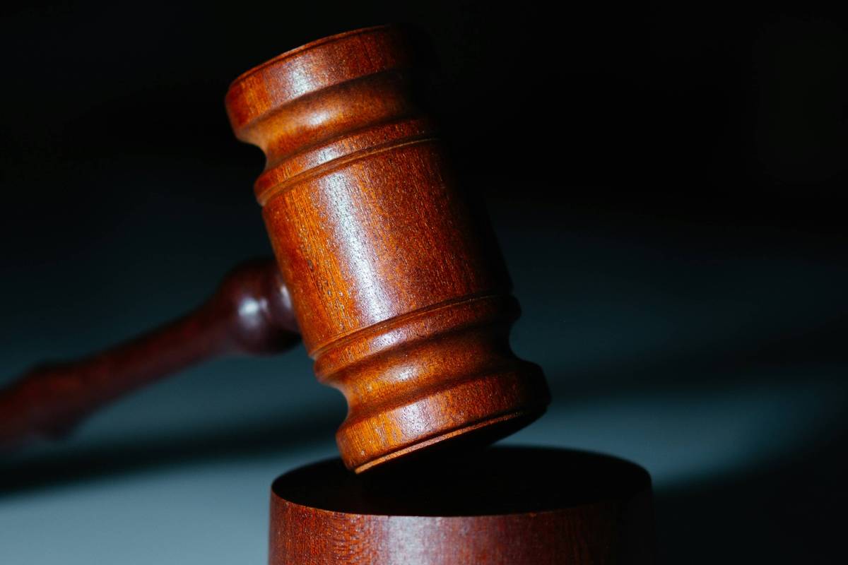 Closeup of wooden gavel on a sound block, dark background.