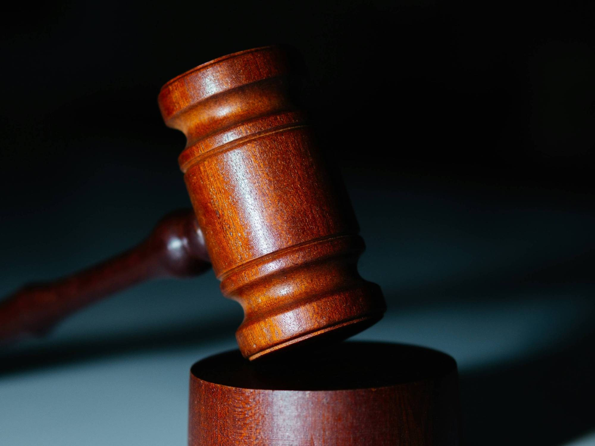 Closeup of wooden gavel on a sound block, dark background.