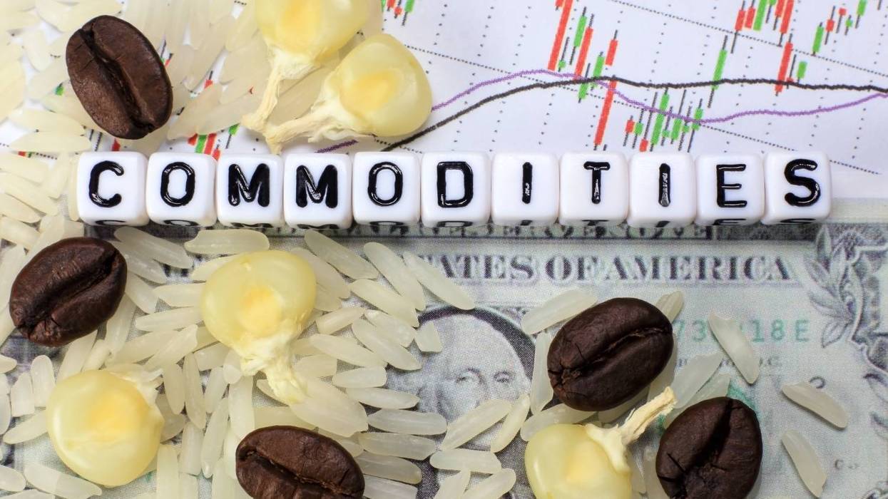 "Commodities" spelled with dice, surrounded by rice, coffee beans, corn, chart and dollar bill.