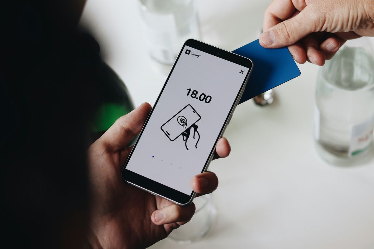 Contactless payment with blue card on smartphone displaying €18.00.