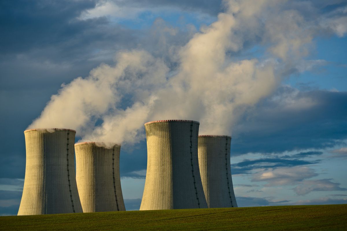 Cooling towers emitting steam under a cloudy sky.