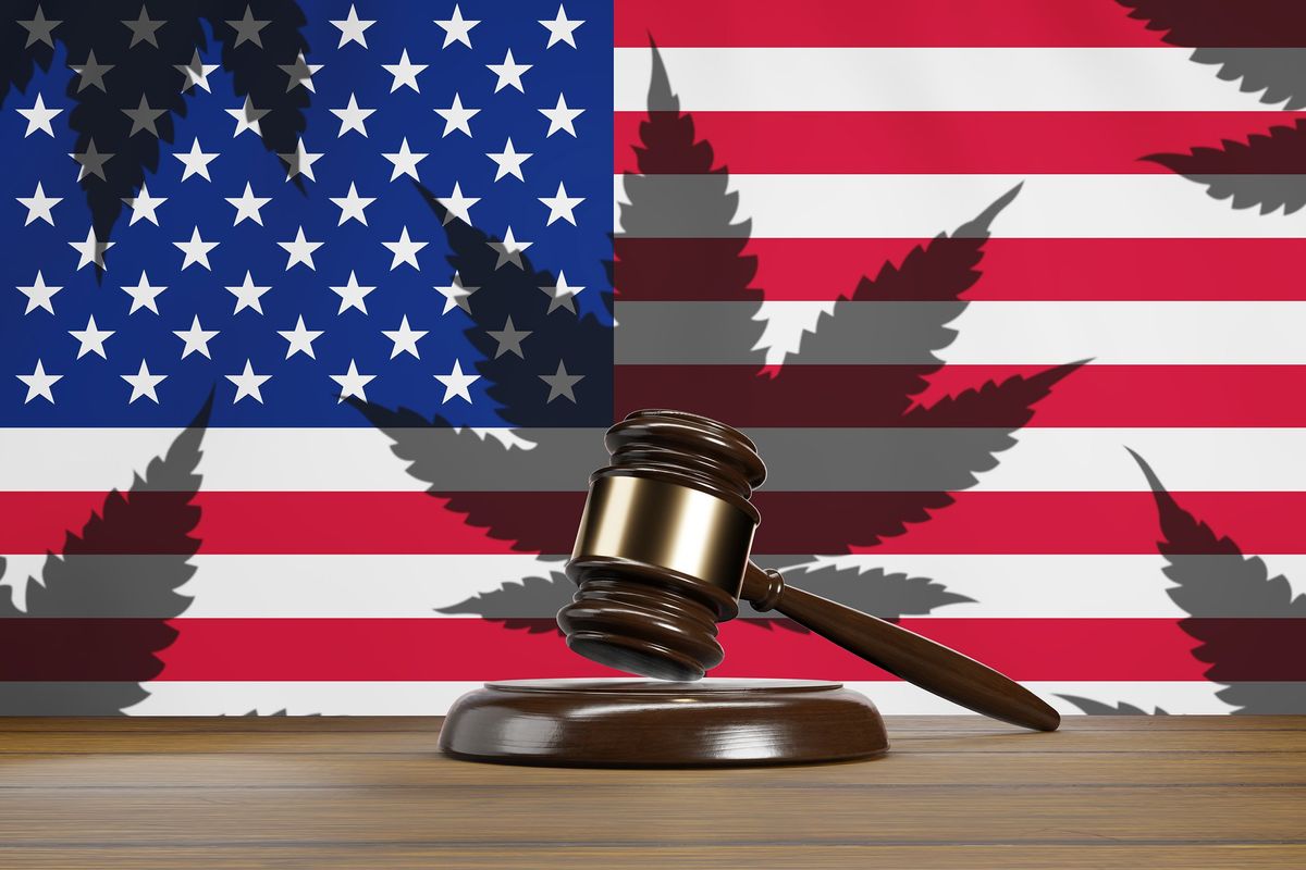 Court gavel in front of national flag of the USA having shadows of cannabis on wooden table.