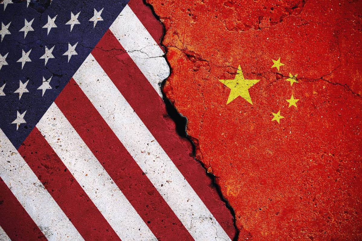 Cracked wall with U.S. and China flags on each side.