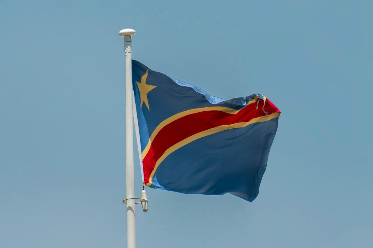 Democratic Republic of Congo flag waving against a clear blue sky.