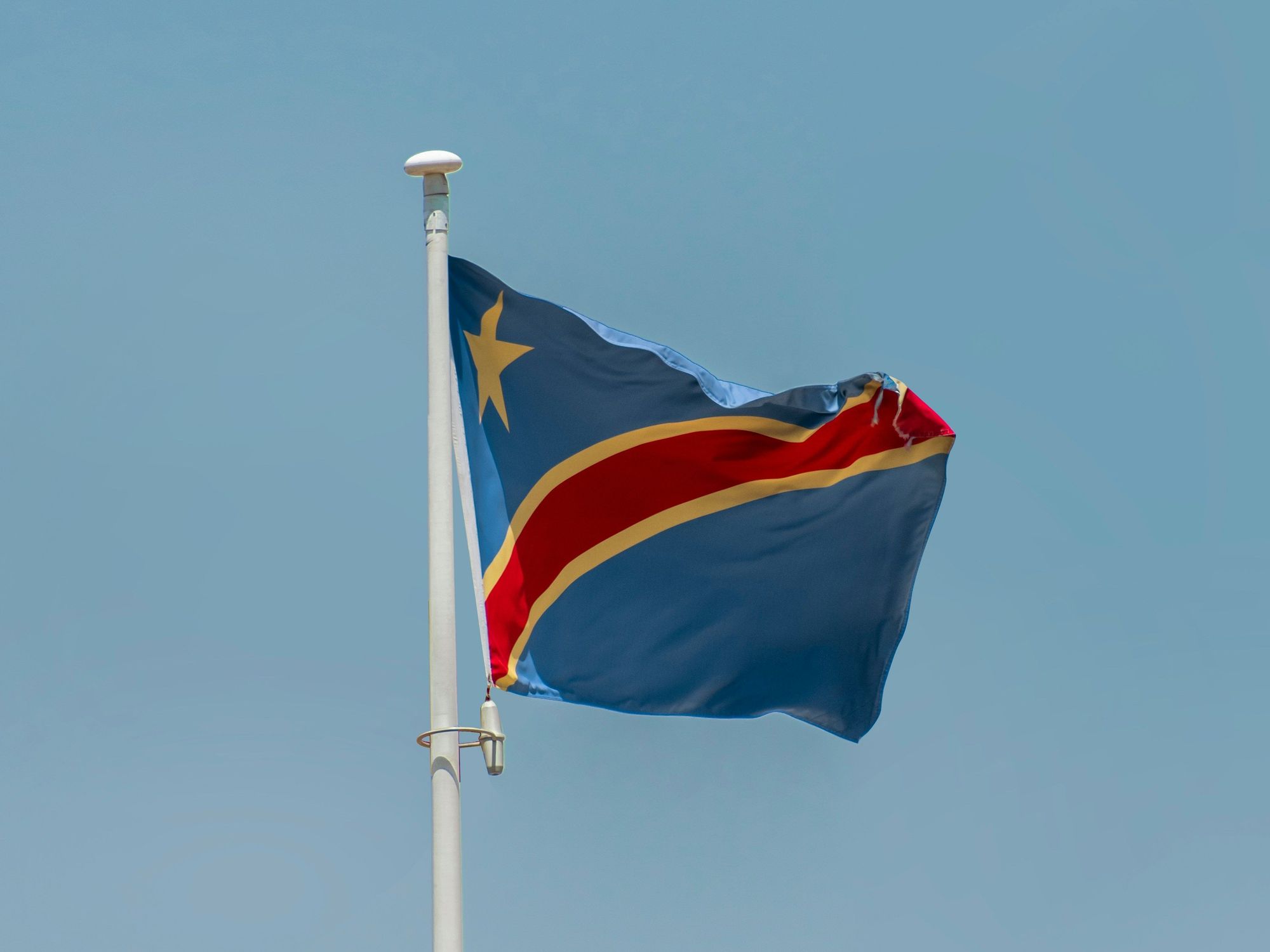 Democratic Republic of Congo flag waving against a clear blue sky.
