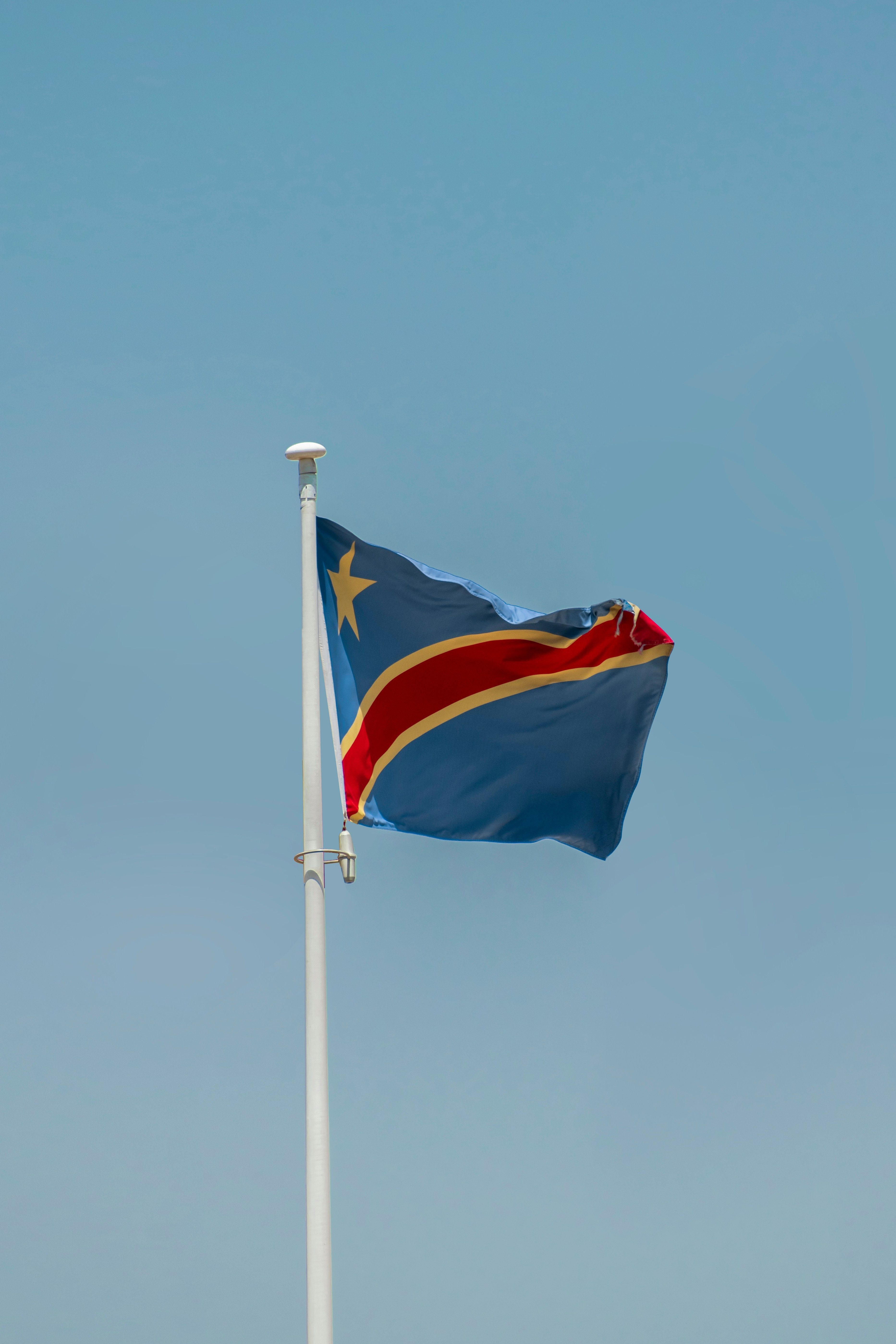 Democratic Republic of Congo flag waving against a clear blue sky.