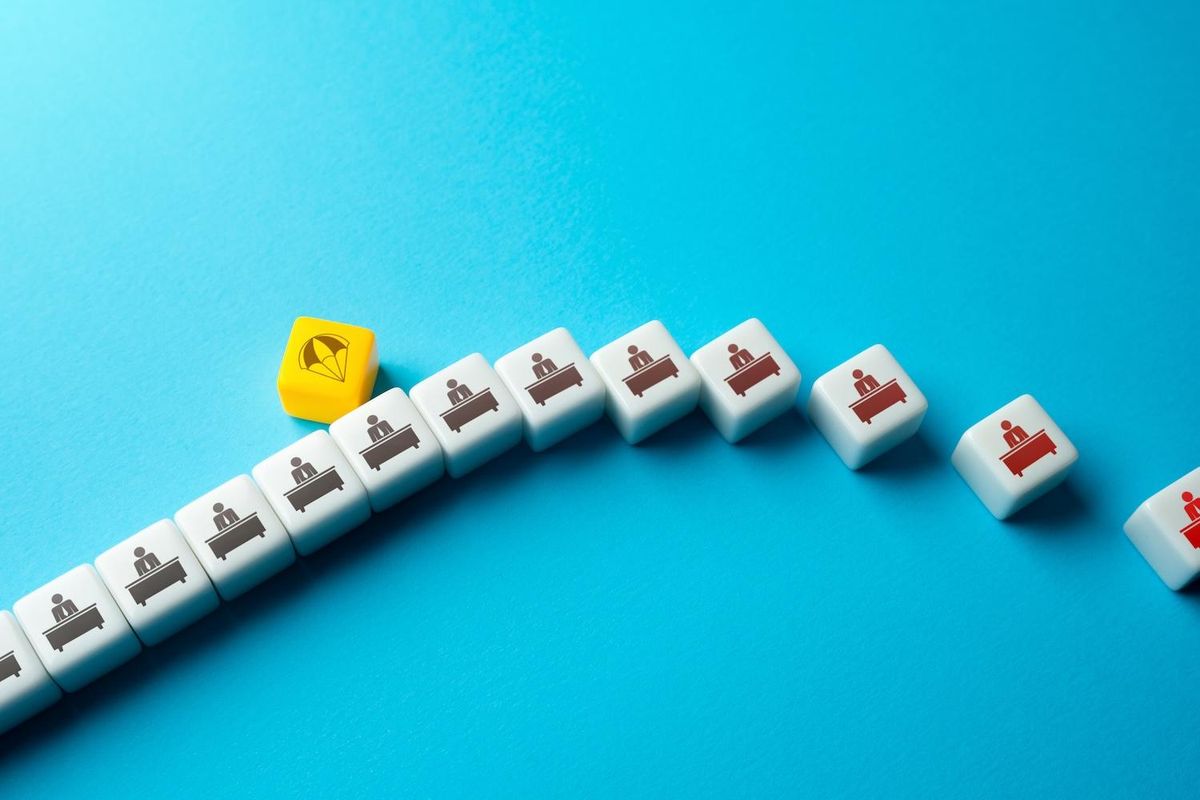 Dice with office worker icons and one yellow parachute die on blue background.