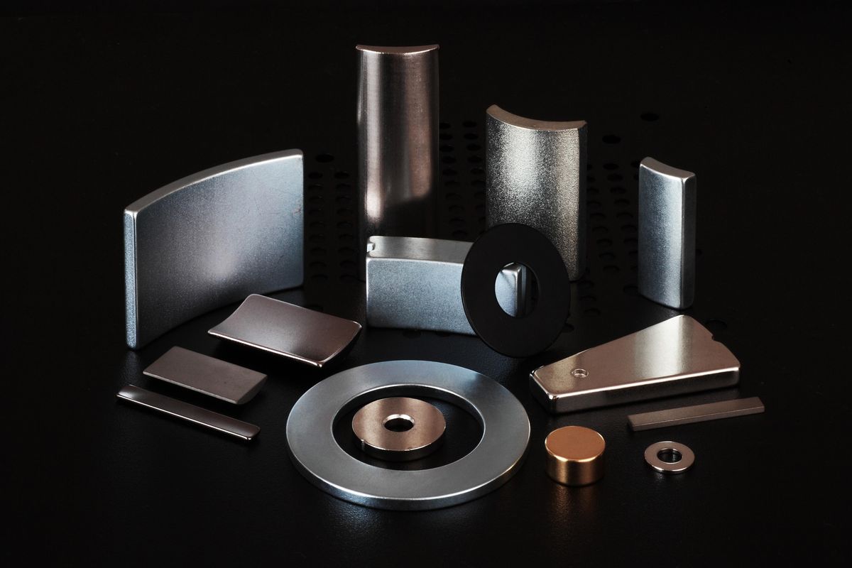 Different types of rare earth magnets laid out over a black surface.