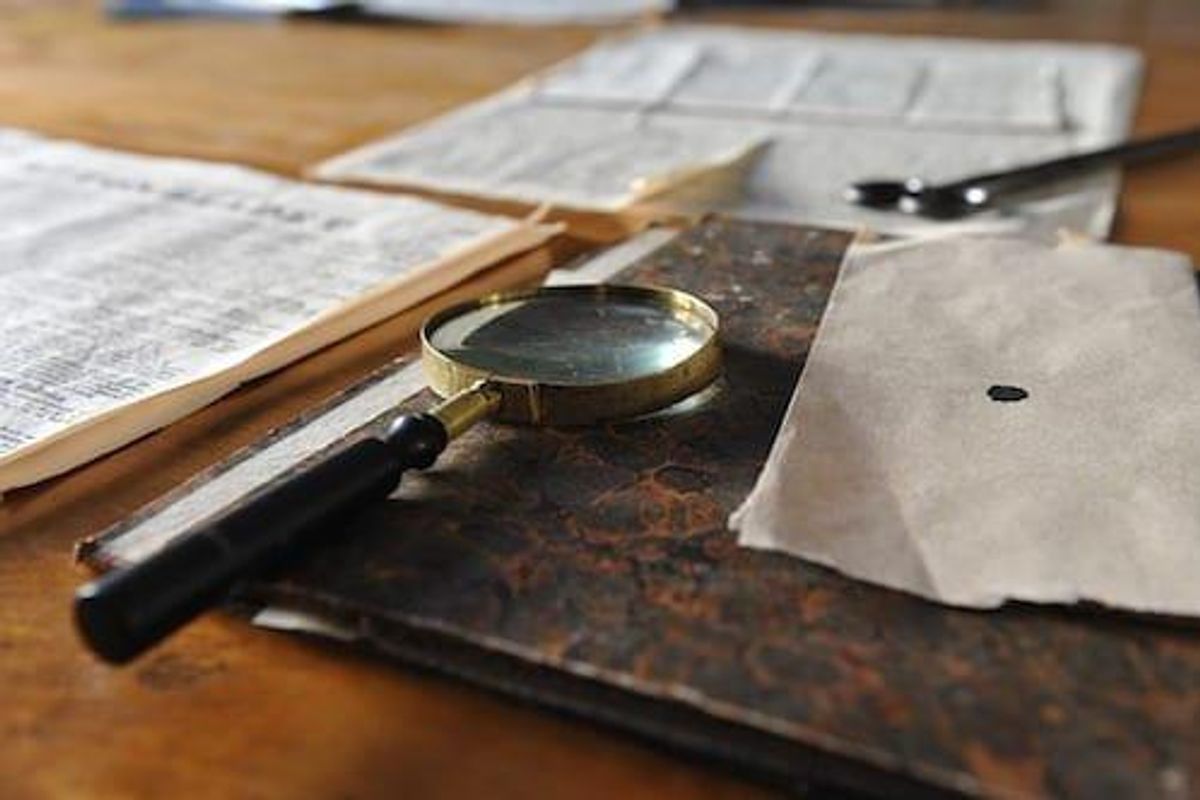 Documents and magnifying glass on wood desk.