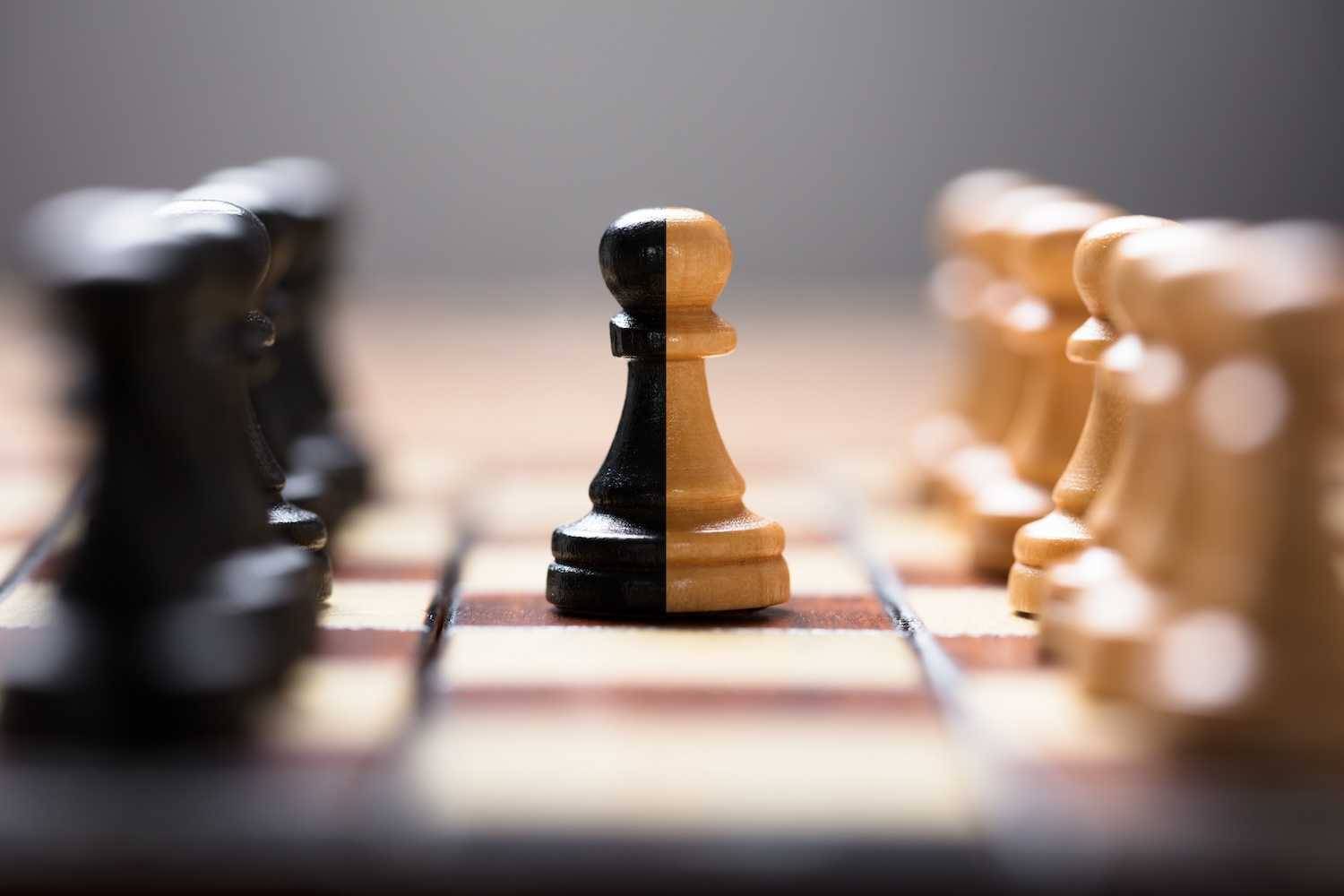 Dual-colored pawn on a chessboard, flanked by black and white pieces.