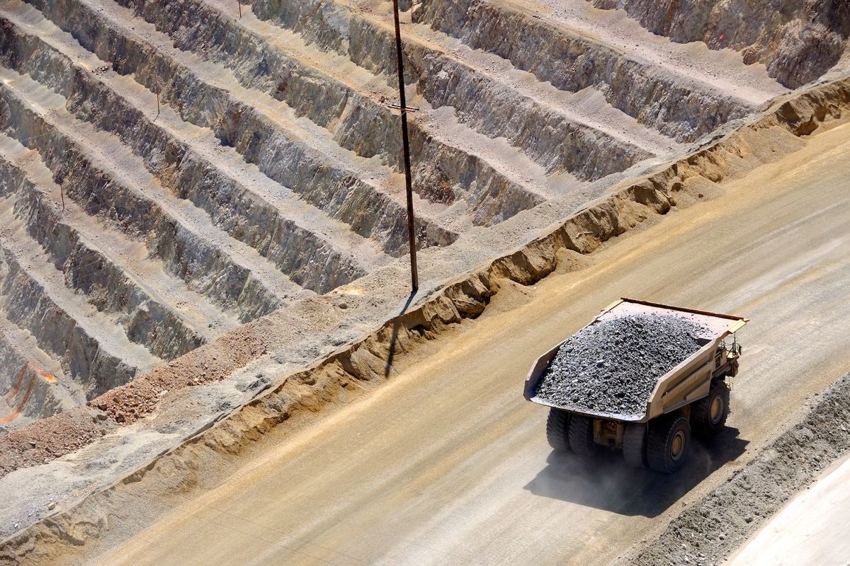 Dump truck carrying ore on a wide dirt road in an open-pit mine.