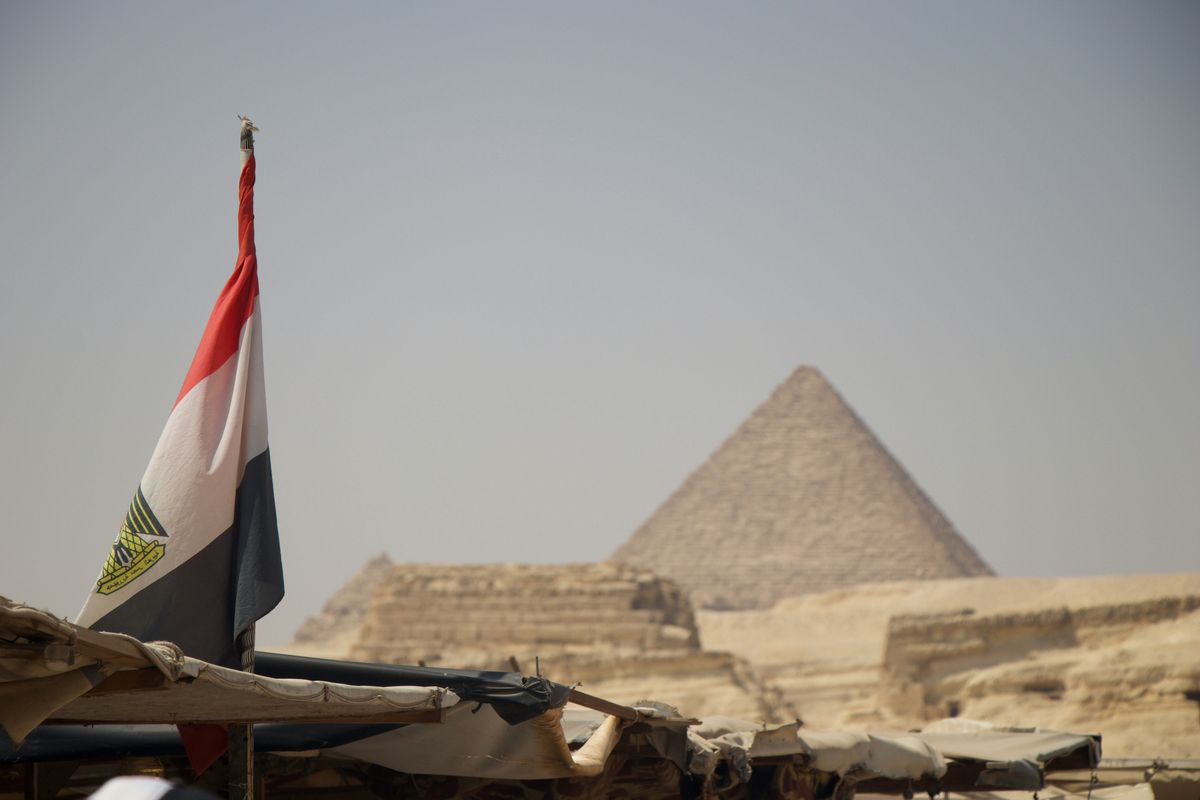Egypt flag with pyramids in background.