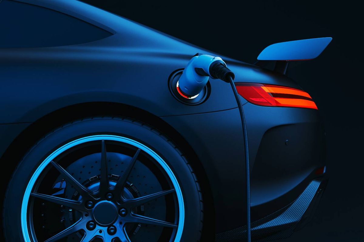 Electric sports car rear with charger plugged in, glowing blue and red lights.