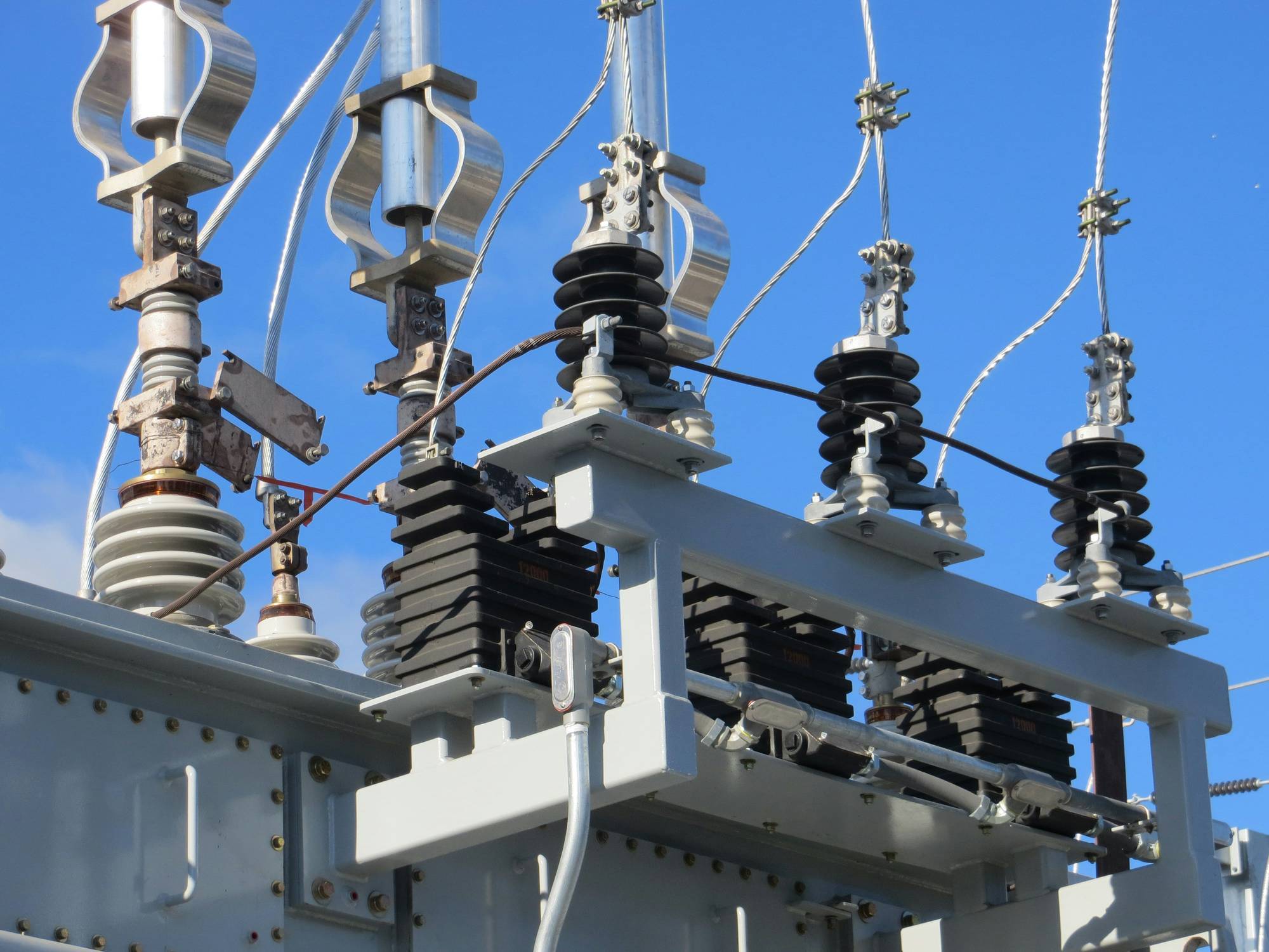 Electrical substation equipment against a clear blue sky.