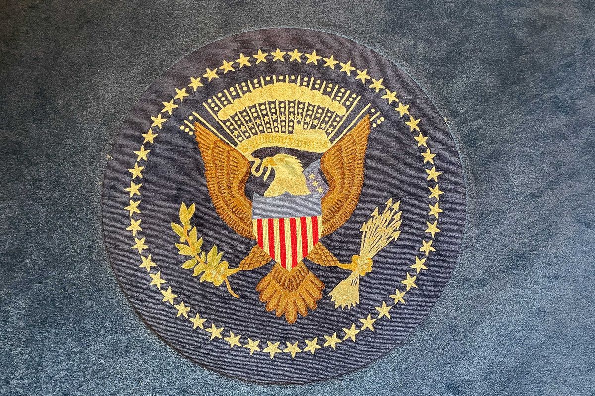Embroidered US presidential seal with an eagle on a blue carpet.