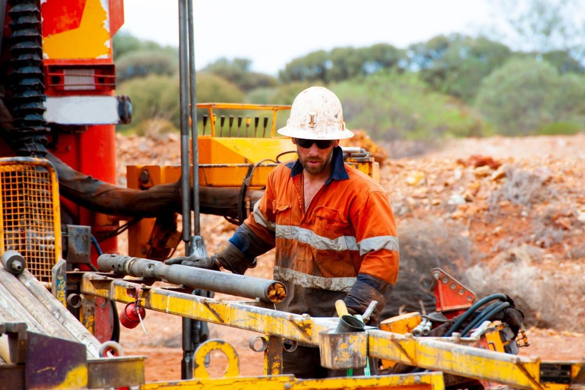 Employee at mining company operating drill machine at project site.