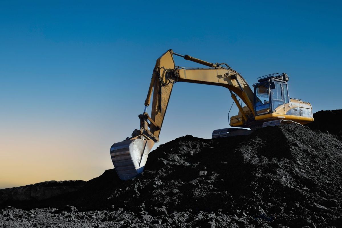 Excavator scooping coal at coal-mining operation.