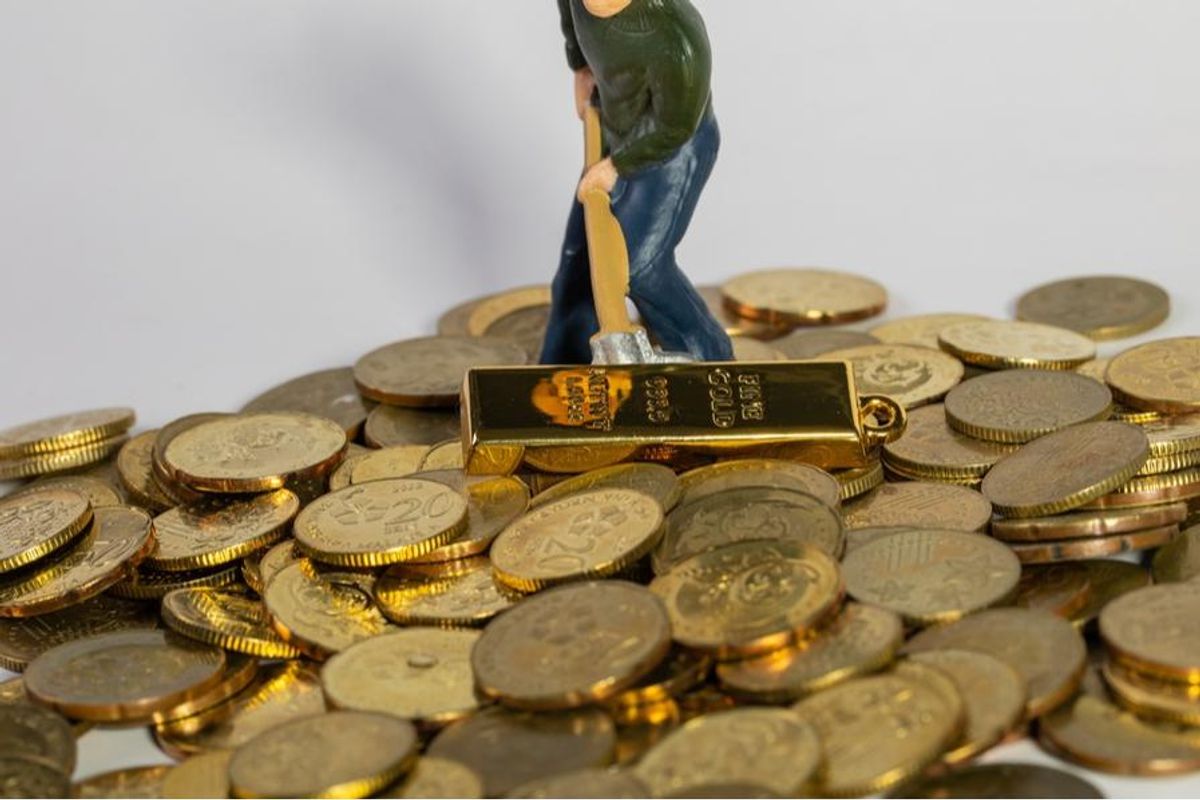 figurine shoveling gold bars and coins