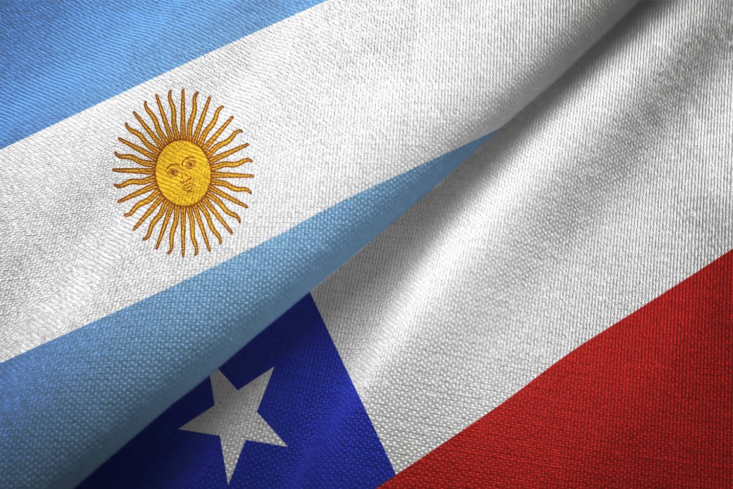 Flags of Argentina and Chile overlapping, displaying colors and symbols on textured fabric.