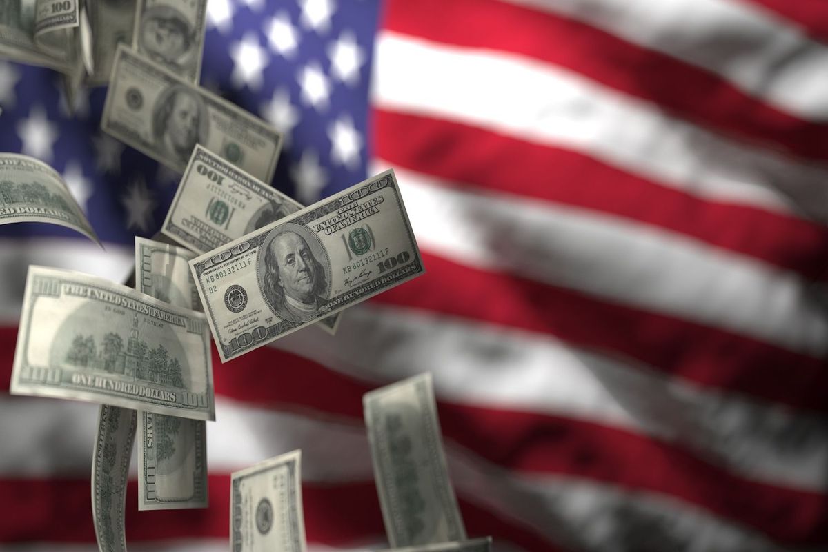Floating US$100 bills over a blurred American flag background.