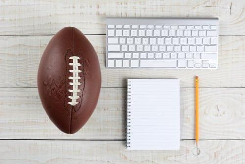 football, computer keyboard, notebook and pencil on a table