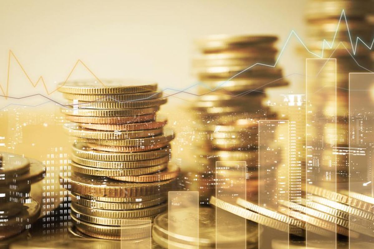 four stacks of gold coins superimposed over a city nightscape