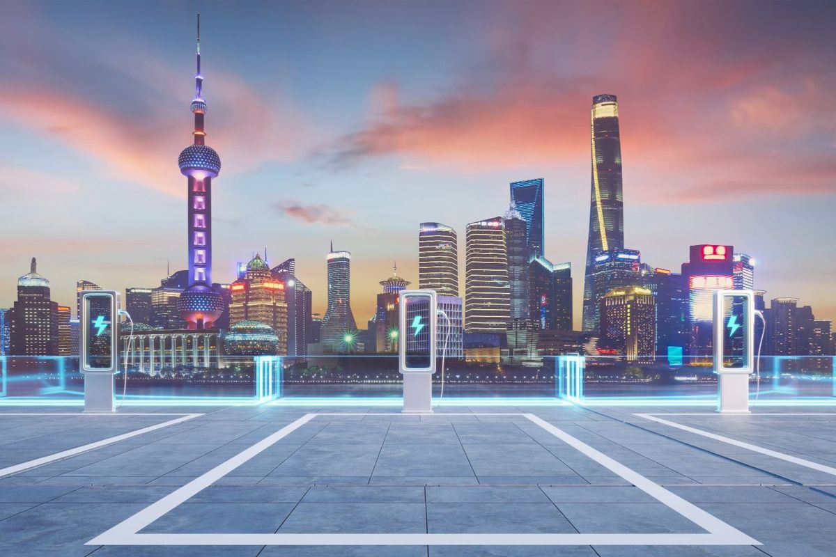 Futuristic skyline with electric car chargers and glowing cityscape at sunset.