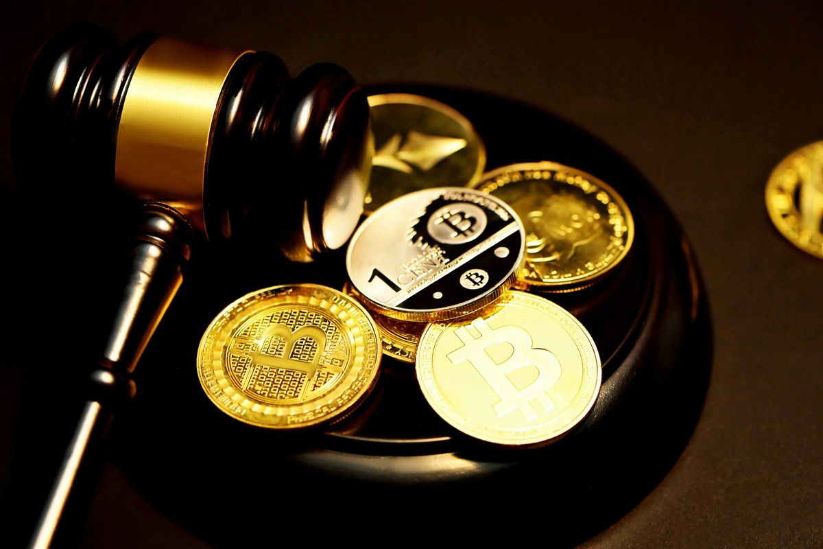 Gavel beside Bitcoin coins on a dark surface.