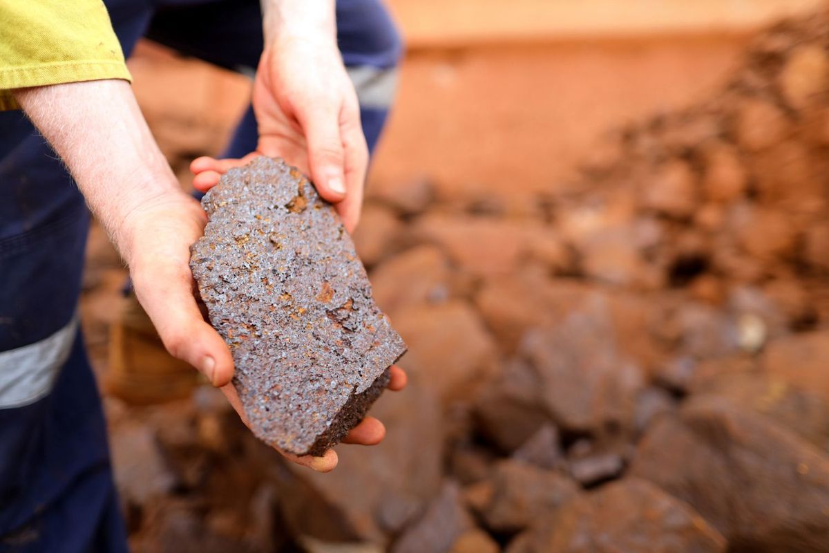 Geologist holding iron ore at Australian mine site.