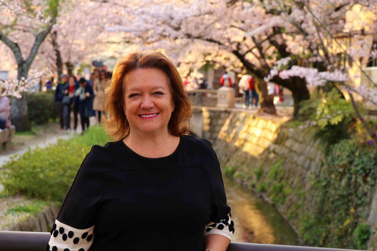 Gina Rinehart, executive chair of Hancock Prospecting, stands in front of cherry blossom trees.