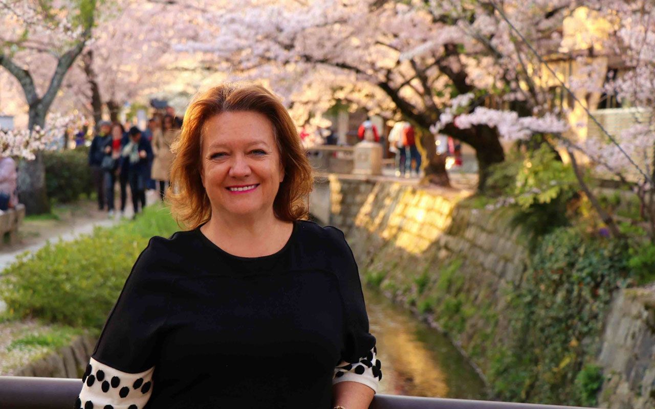 Gina Rinehart, executive chair of Hancock Prospecting, stands in front of cherry blossom trees.