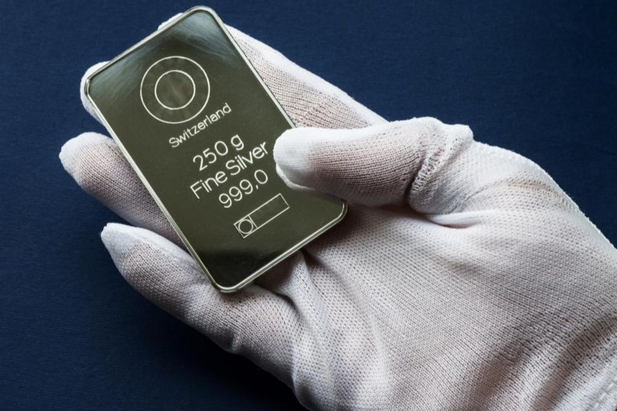 gloved hand holding silver bar