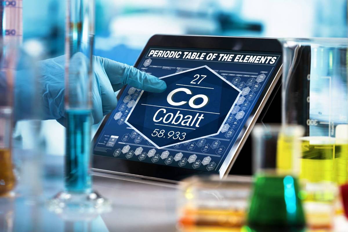 Gloved hand selecting cobalt on a digital periodic table, surrounded by lab equipment.