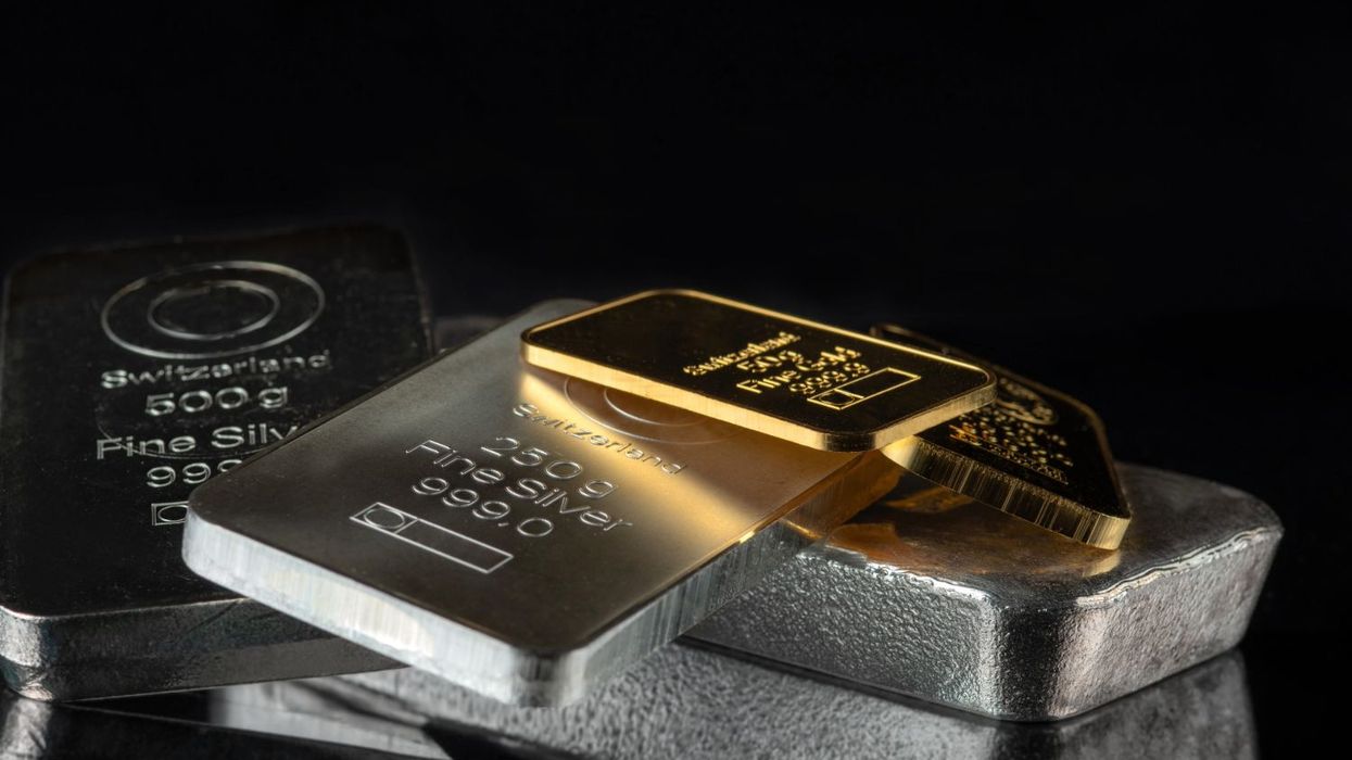 Gold and silver bars stacked on a reflective black surface.