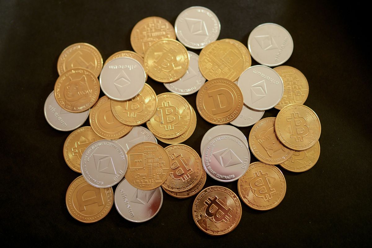 Gold and silver coins featuring various cryptocurrency logos on a black background.