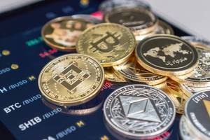 Gold and silver cryptocurrency coins stacked on a digital screen displaying market data.